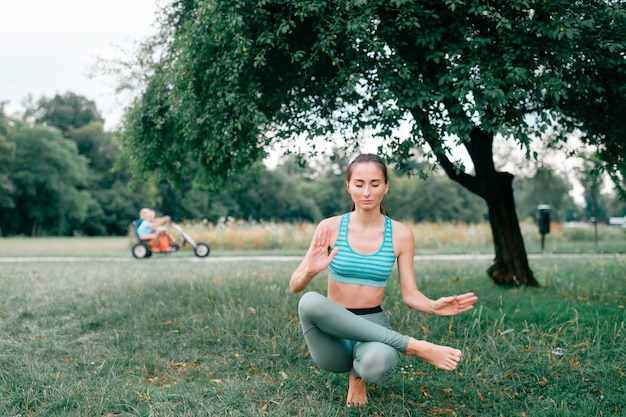 Fille brune de remise en forme, faire du yoga en plein air