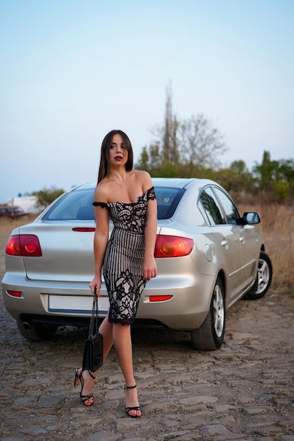 fille brune en robe de soirée et chaussures près de la voiture