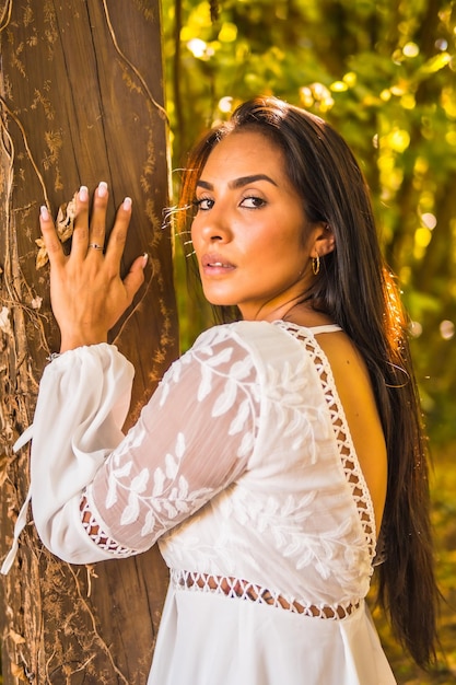 Photo fille brune de style de vie aux cheveux raides dans une belle robe blanche dans un parc