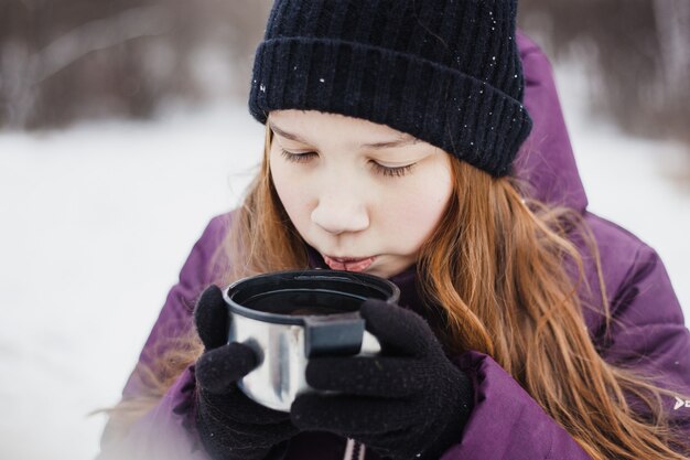 Fille buvant du thé ou une boisson dans un thermos, promenade d'hiver, randonnée, hiver, vêtements d'hiver