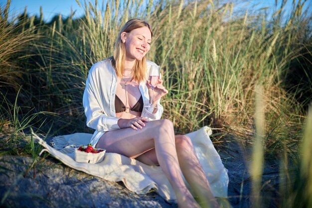 Photo une fille buvant du vin sur la plage.