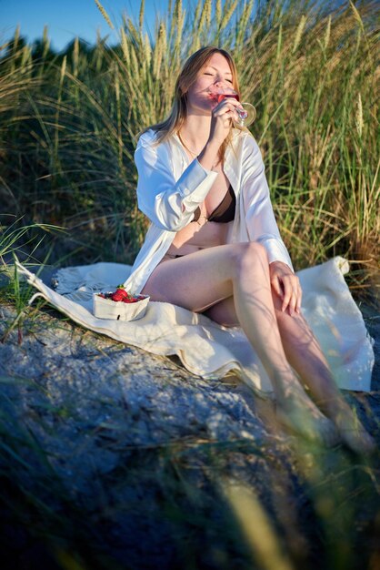 Photo une fille buvant du vin sur la plage.