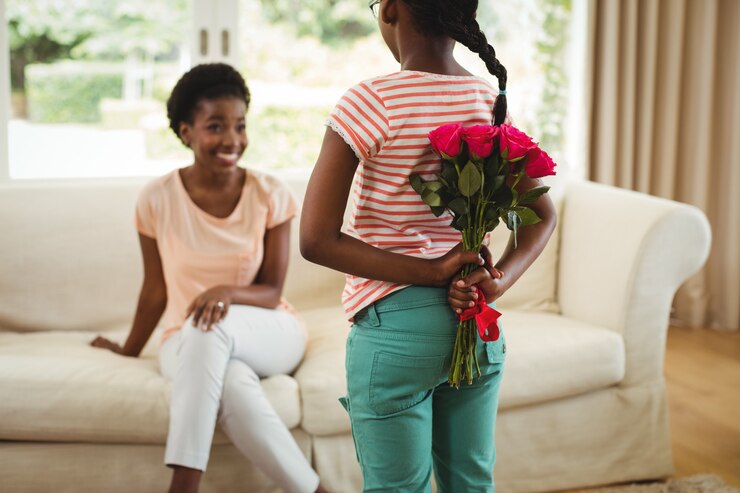 Fille cachant des fleurs derrière son dos pour la mère