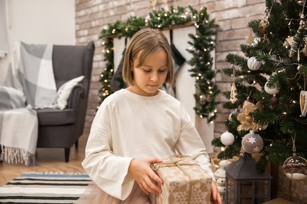 Fille avec un cadeau à l'arbre de Noël