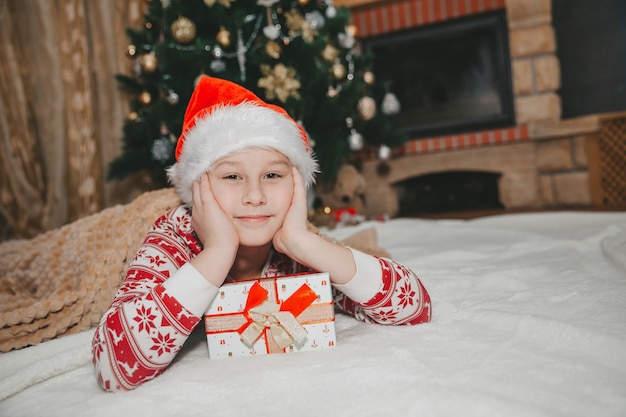 Fille avec un cadeau à l'arbre de Noël