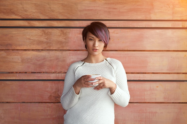 Fille avec café sur mur en bois