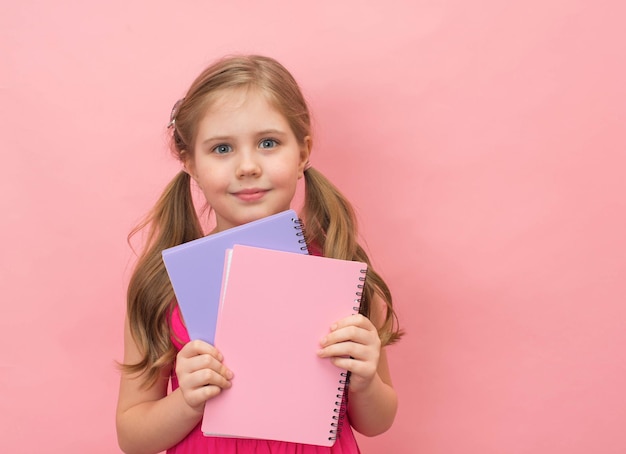 Fille avec des cahiers ou des cahiers sur fond rose