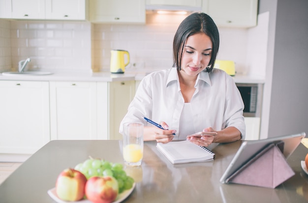 Une fille calme et occupée est assise à table et travaille.