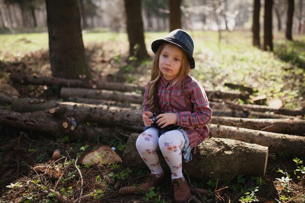 Fille avec caméra assis sur le bois