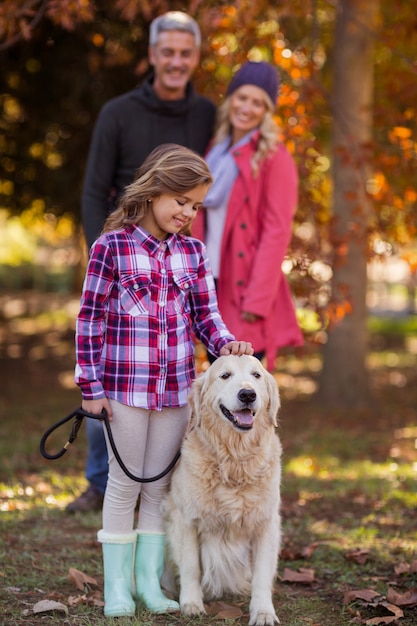 Fille caressant le chien pendant que les parents au parc