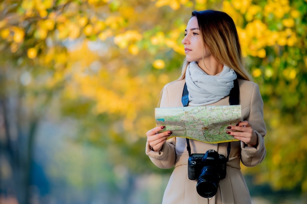 Fille avec carte et caméra à la recherche de chemin dans la rue.