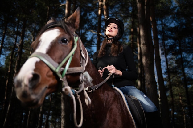 Fille avec casque à cheval dans la forêt