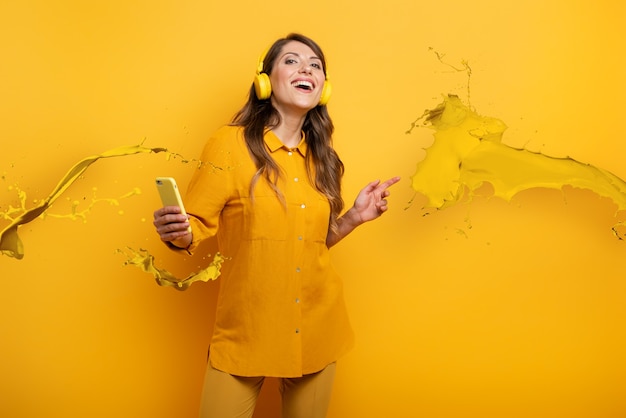 Fille avec un casque jaune écoute de la musique et des danses. expression émotionnelle et énergétique