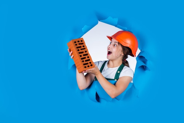 Fille en casque joue au constructeur avec des briques construisant une maison Enfant ingénieur en construction adolescent est ouvrier du bâtiment Artisan professionnel ou ouvrier Espace de copie de la journée internationale des travailleurs