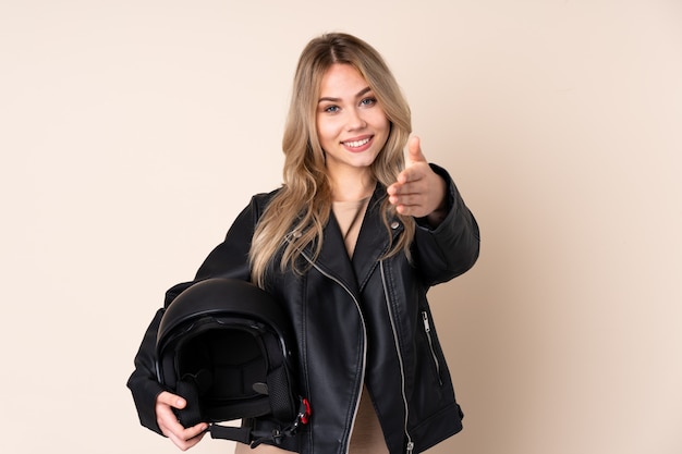 fille avec un casque de moto sur le mur beige se serrant la main pour fermer une bonne affaire