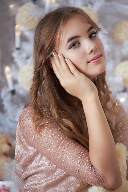 Fille caucasienne avec un beau visage et de longs cheveux sur le fond de l'arbre de Noël
