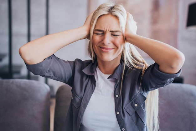 Une fille caucasienne blonde bouleversée se serrant la tête par les mains avec une expression de visage frustrée ressent des maux de tête une femme en difficulté des problèmes de chagrin