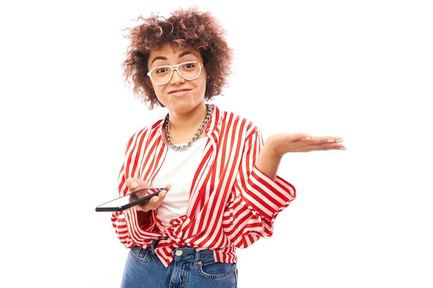 Fille caucasienne bouclée heureuse avec le smartphone d'isolement sur le message textuel de fond de studio blanc