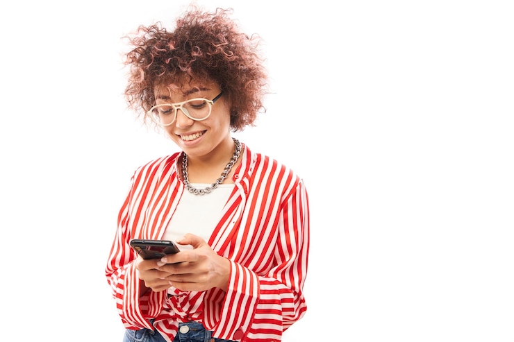 Photo fille caucasienne bouclée heureuse avec le smartphone d'isolement sur le message textuel de fond de studio blanc