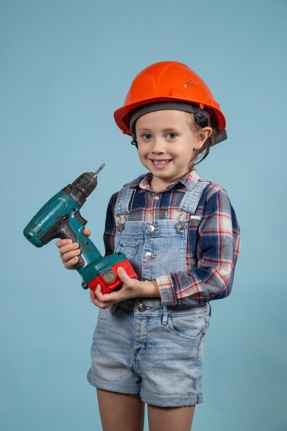 Une fille caucasienne heureuse porte un casque de sécurité orange, tenant un tournevis à la main. Concept de construction et de réparation.