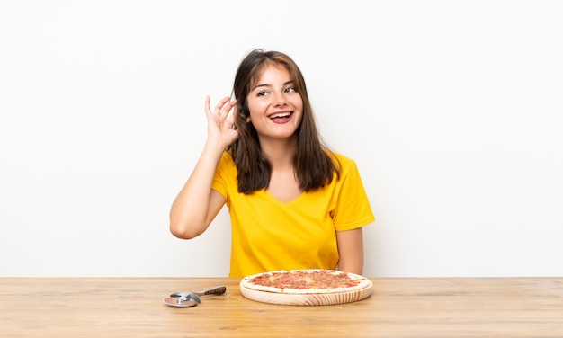 Fille caucasienne avec une pizza écoute quelque chose