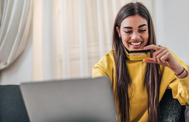 Fille caucasienne souriante tenant une carte de crédit en lisant le numéro de carte