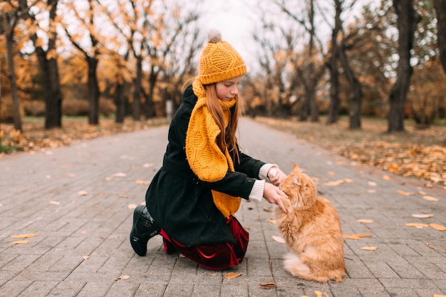 fille caucasienne avec des taches de rousseur face jouant son joli chaton sur la route dans le parc en automne.