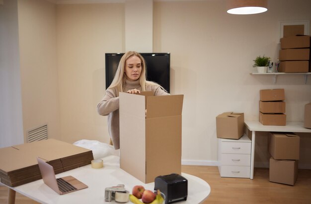 Fille caucasienne tapant des boîtes pour emménager dans un nouvel appartement