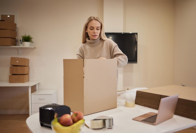 Fille caucasienne tapant des boîtes pour emménager dans un nouvel appartement