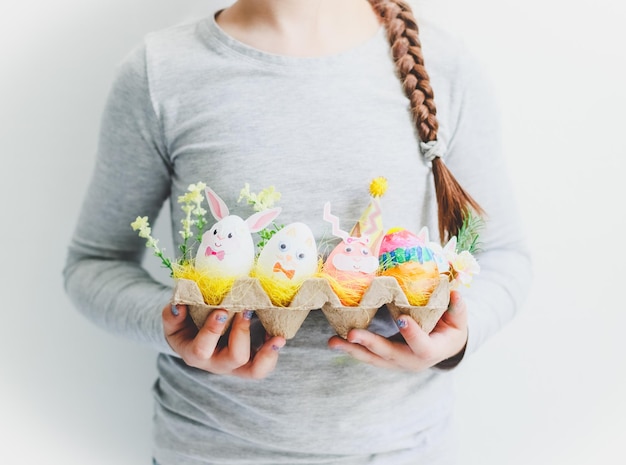 Fille caucasienne tenant une boîte avec des oeufs de lapin de Pâques faits maison sur fond blanc