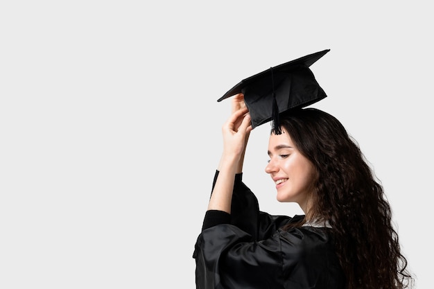 Fille célibataire surprise en robe de graduation et bonnet. Enseignement à distance en ligne. Étudier à la maison. Diplôme universitaire.