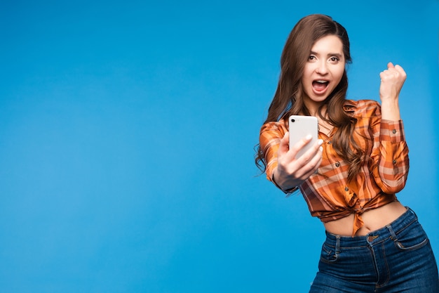 Fille chanceuse en chemise à carreaux prenant selfie et souriant