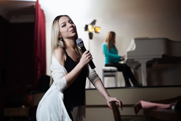 Une Fille Chante Dans Un Restaurant Et Derrière Son Collègue Joue Du Piano.