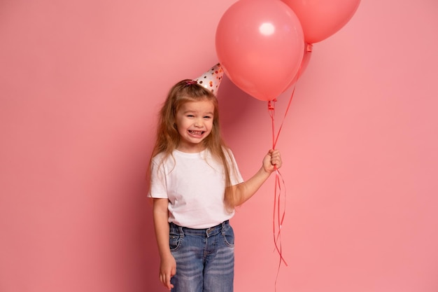 Une fille avec un chapeau de fête et un ballon rose