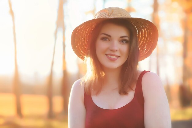 Une fille avec un chapeau lors d'une promenade dans le parc Une fille avec un panier se promène en automne Une fille marche le long de la route au coucher du soleil