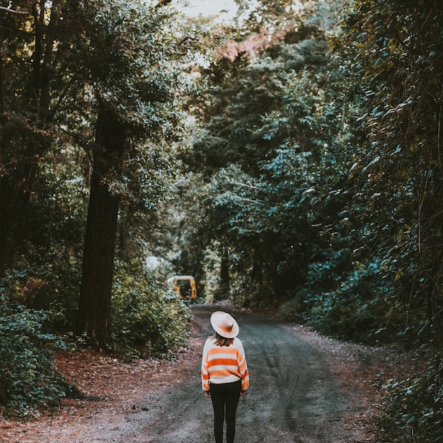 fille avec un chapeau marchant dans les bois