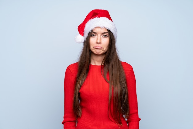 Fille avec un chapeau de Noël isolé bleu triste