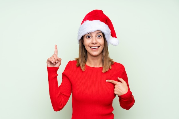 Fille avec un chapeau de Noël sur vert isolé avec une expression faciale surprise