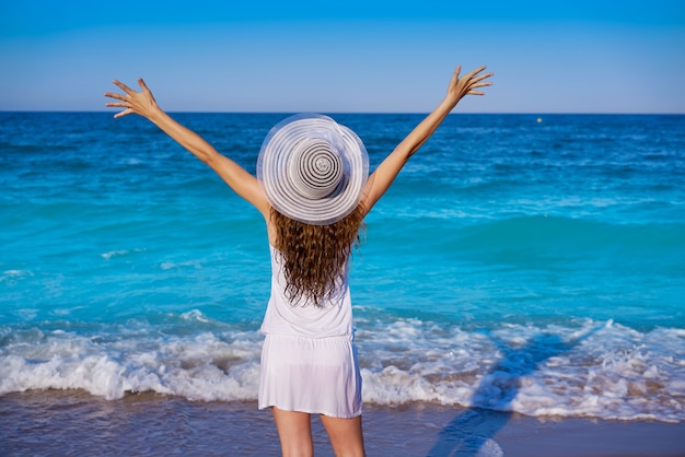 Fille avec chapeau de plage en mer bras ouverts