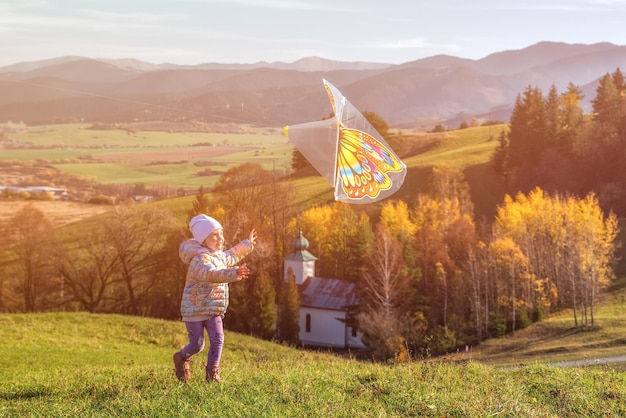 Fille chassant un cerf-volant dans un champ au coucher du soleil