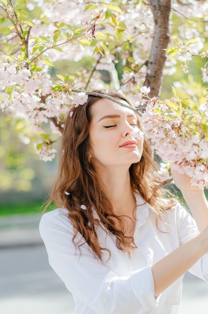 fille en chemise blanche se tient près de la sakura