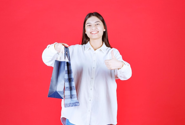 Fille En Chemise Blanche Tenant Plusieurs Sacs à Provisions Et Montrant Un Signe Positif De La Main