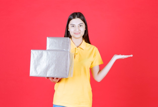 Fille en chemise jaune tenant une boîte cadeau en argent