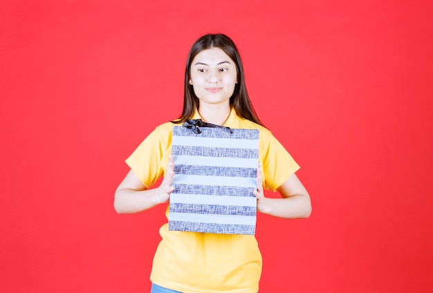 Fille en chemise jaune tenant un sac bleu