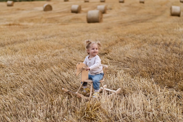 une fille sur un cheval de bois. l'enfant monte. champ