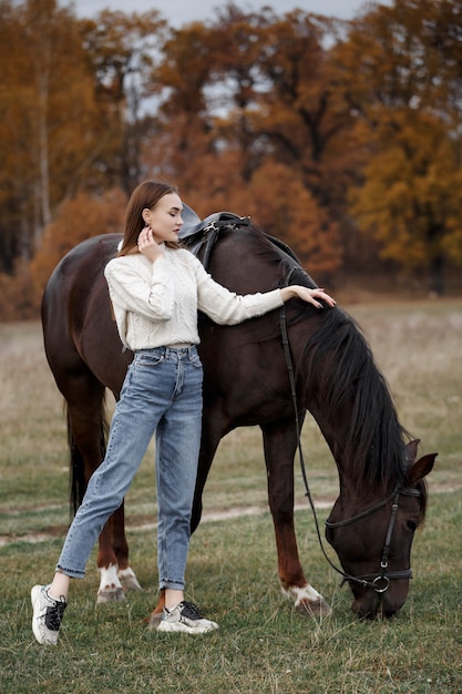 Une fille avec un cheval dans la nature, une promenade d'automne avec un animal