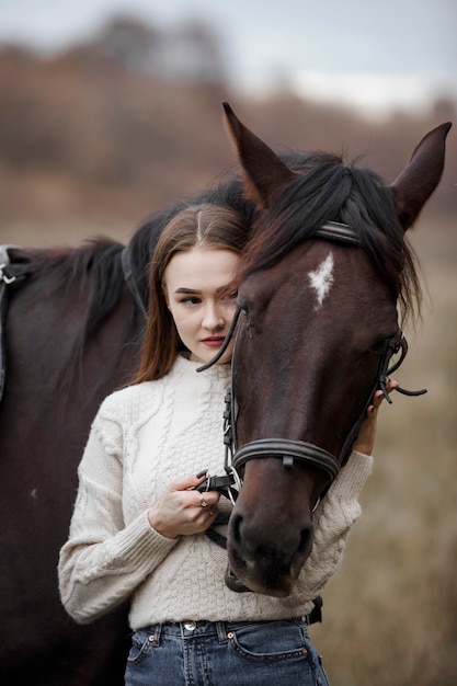 Une fille avec un cheval dans la nature, une promenade d'automne avec un animal