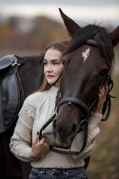 Une fille avec un cheval dans la nature, une promenade d'automne avec un animal