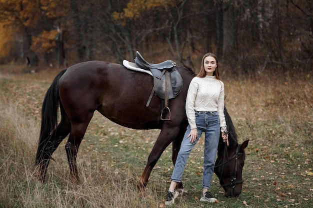 Une fille avec un cheval dans la nature, une promenade d'automne avec un animal