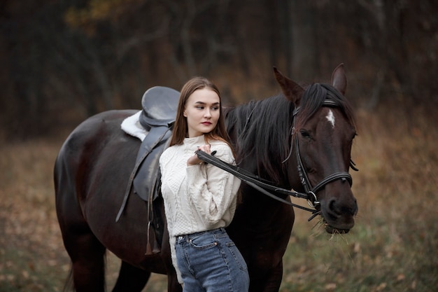 Une fille avec un cheval dans la nature, une promenade d'automne avec un animal